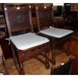 A set of four early 20th Century polished oak panel back dining chairs with incised decoration and