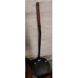 An antique wrought iron chestnut roaster with wooden handle