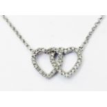 A hallmarked 375 white gold pendant necklace, with diamond encrusted double heart motif