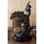 A Remington style cast metal figure of a mounted cowboy with applied patination, set on a polished