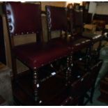 A set of six stained oak framed panel back dining chairs with studded red leather upholstery, set on