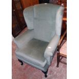 A modern wing back armchair upholstered in frosted green velour, set on polished wood front cabriole