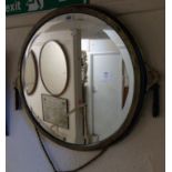 A 22" diameter Art Deco brassed metal framed bevelled wall mirror, with flanking decorative