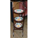 An early 20th Century mahogany and strung three tier cake stand with brass handle to top and three