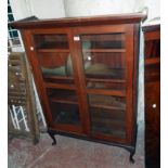 A 36 1/2" early 20th Century stained mixed wood four shelf book cabinet enclosed by a pair of glazed