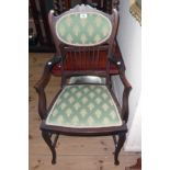 An Edwardian stained wood framed elbow chair with upholstered back and seat panels, set on