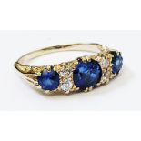 A high carat yellow metal ring, set with three sapphires interspersed with two pairs of small