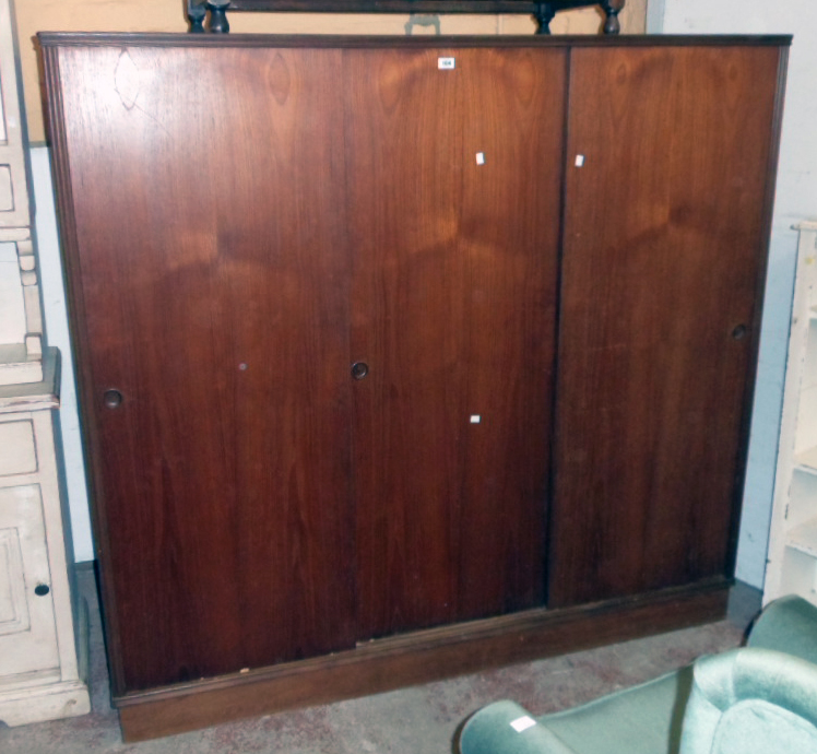 A 5' 11 1/2" mid 20th Century teak effect triple wardrobe with hanging space and shelves enclosed by