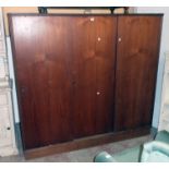 A 5' 11 1/2" mid 20th Century teak effect triple wardrobe with hanging space and shelves enclosed by