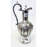 A silver plated claret jug with ornate decoration and scroll handle