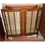 A 3' 10" 20th Century polished walnut double bow front display cabinet with glass shelves and