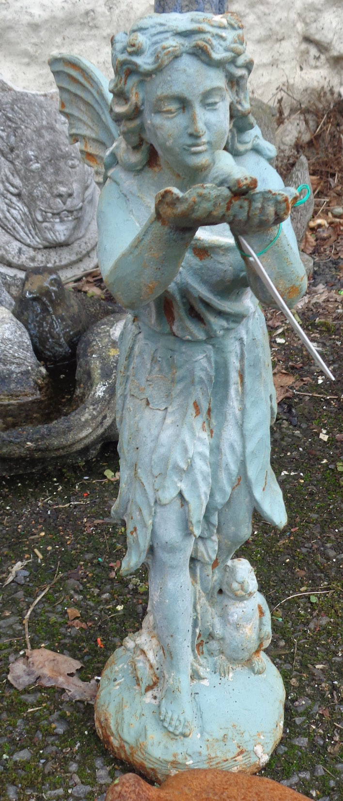 A painted cast iron garden fairy standing and holding a bird