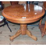 A 24" diameter modern varnished oak pedestal table, set on heavy turned pillar and tripod base