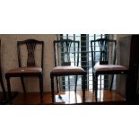 A set of four reproduction stained wood framed dining chairs with pierced splat backs and