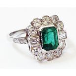 A marked PLAT Art Deco style white metal ring, set with central emerald within an eight stone