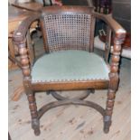 An early 20th Century oak framed tub chair with rattan back and studded upholstered seat, set on