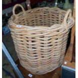 A 24" diameter heavy wicker log basket, with flanking loop handles