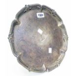 A 12" diameter Georgian silver salver with cast rim, central armorial, set on claw and ball feet -