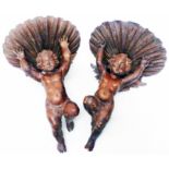 A pair of continental carved wood wall brackets in the form of cherubs holding seashells
