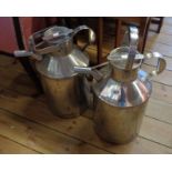 A pair of large industrial stainless steel jugs with lids