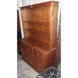 A 4' 2" modern polished pine two part dresser with open plate rack over a base with three drawers