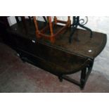 A 4' 6" antique stained oak gateleg dining table, set on turned supports