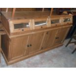 A 6' 2" modern waxed pine dresser base with four slope fronted and glazed storage compartments