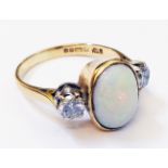 A hallmarked 750 gold ring, set with central oval opal flanked by two diamonds