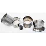 Three silver napkins rings, of varying design and another - sold with a silver thimble