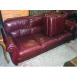 A 7' 3" modern three seater settee upholstered in oxblood coloured leather - sold with a locker