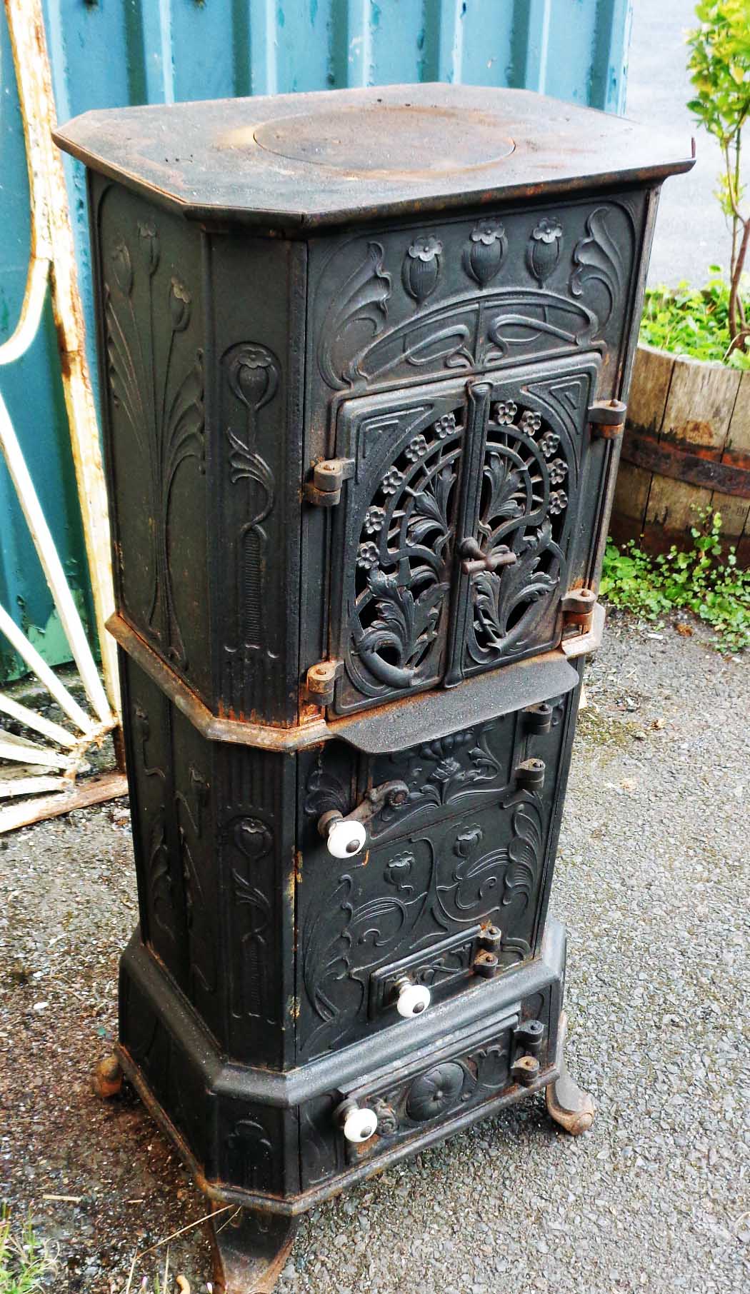 A 16 1/2" modern upright cast iron wood burner in the Art Nouveau style, with moulded flower heads