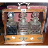 A late Victorian oak and gothic style metal mounted three bottle tantulus with bracket locking front