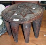 A 14" diameter African carved wood tribal stool, with star motif to top and tapered legs - a/f