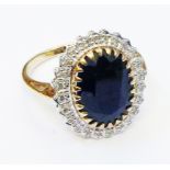 A import marked 375 gold ring set with large central oval dark sapphire within an illusion set