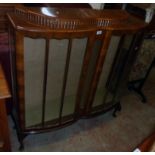 A 3' 10" 20th Century polished walnut double bow front display cabinet with glass shelves and