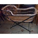 An old wicker Moses basket cot, set on a painted iron folding stand
