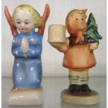 A pair of Hummel figures of an angel praying and a girl carrying a small Christmas tree