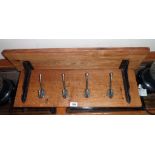 A 29" stained wood wall mounted coat rack with bracketed shelf and four hooks