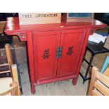 A 3' 11" Chinese red lacquered cabinet with wide bracketed top, shelves and two drawers enclosed