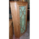 A 32" antique waxed pine corner cabinet of asymmetrical design with painted scallop shelves enclosed