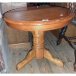 A 24" diameter modern varnished oak pedestal table, set on heavy turned pillar and tripod base