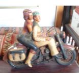 A wooden figure of two people on a motorbike