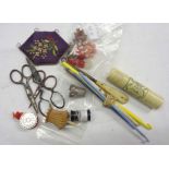 A collection of sewing items including tape measure, needle case, thimbles, scissors, etc.