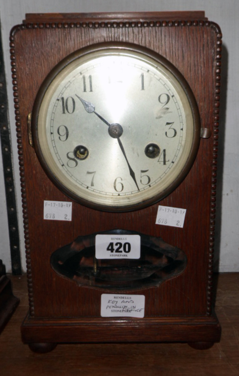 An early 20th Century oak cased mantel clock with silvered dial, visible pendulum and eight day gong