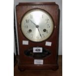 An early 20th Century oak cased mantel clock with silvered dial, visible pendulum and eight day gong