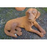 A cast iron garden recumbent dog with rusted finish