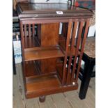 A 19" Edwardian walnut revolving bookcase with moulded slats, set on brown porcelain casters