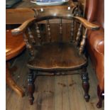 An antique smoker's bow elbow chair with moulded solid elm seat, set on turned supports