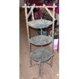 An old rustic three tier cake stand with rose bush supports and lacquered doily surfaces in metal