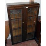 A 30" 1930's polished oak four shelf book cabinet enclosed by a pair of leaded glazed panel doors